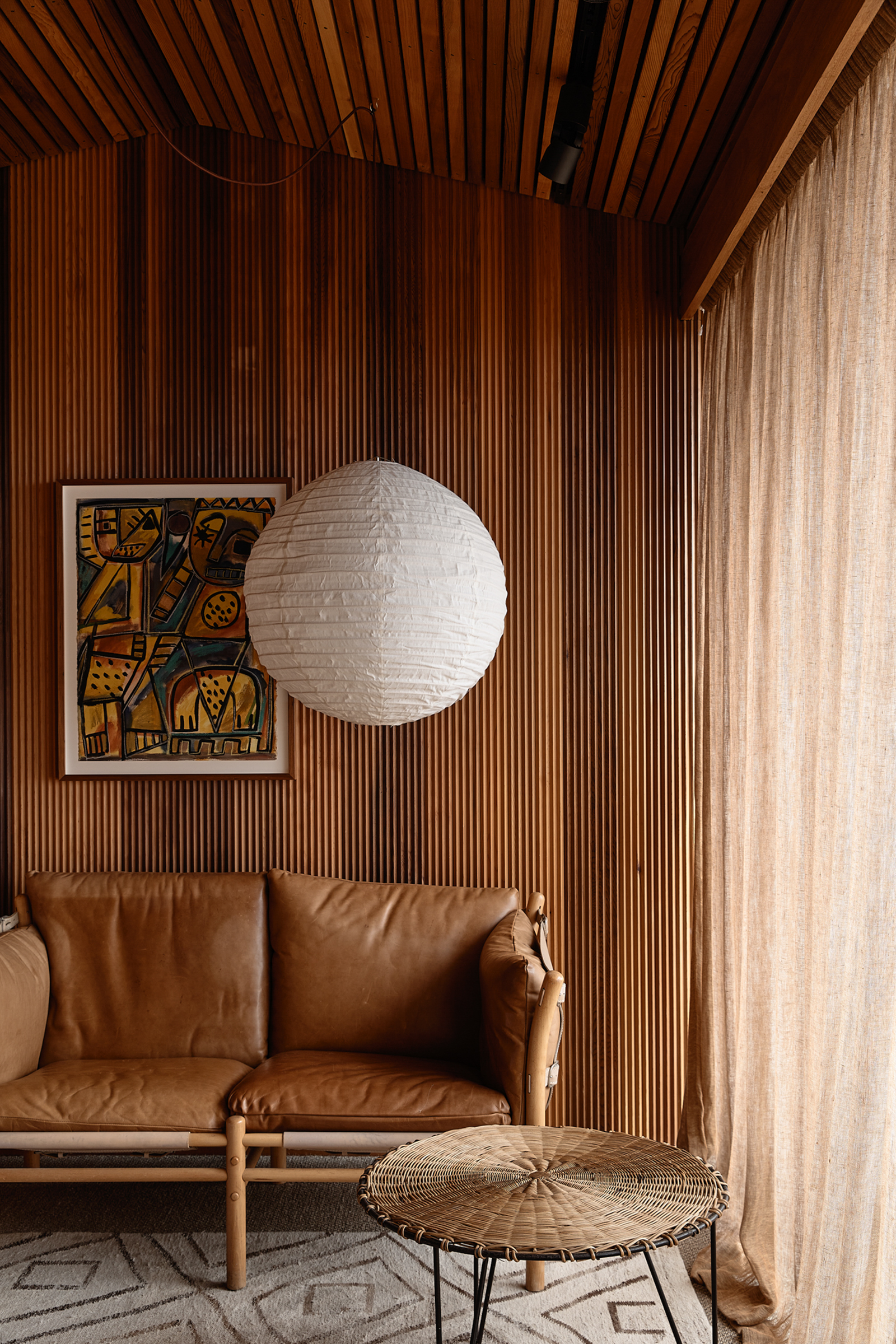 A lantern and couch in a living room with timber walls.
