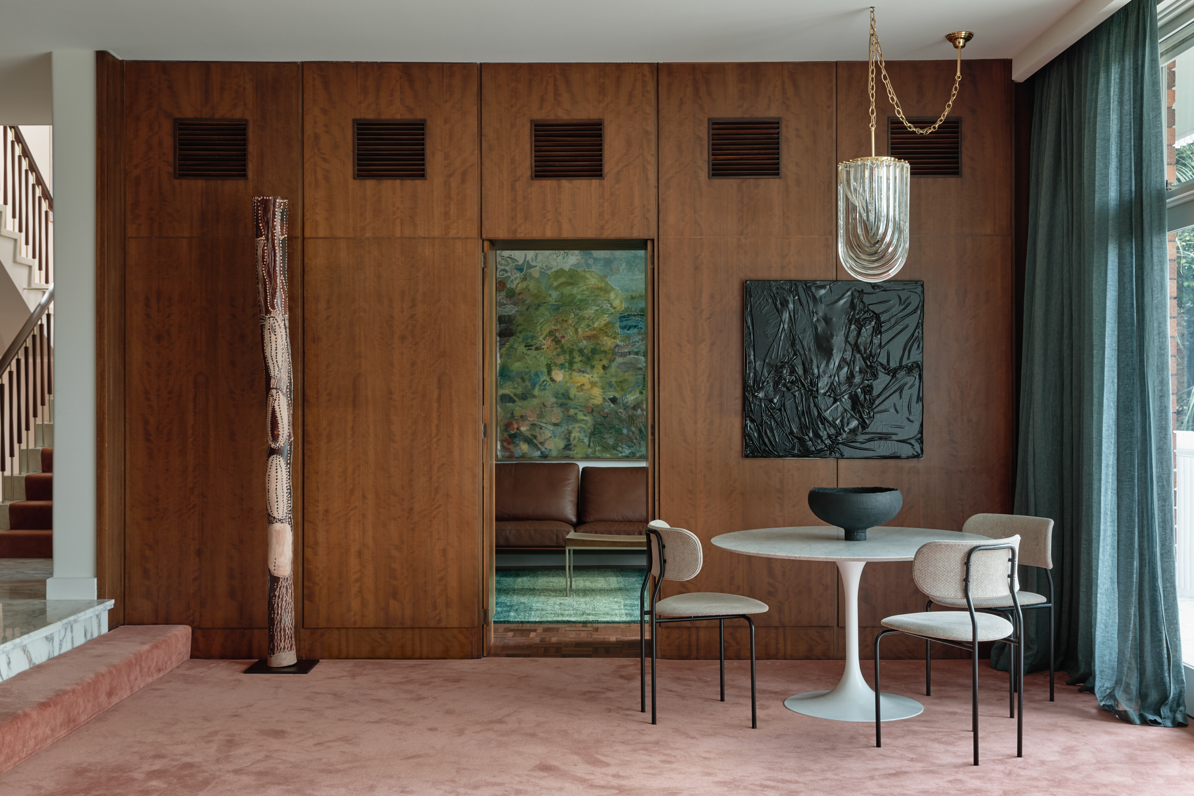 A sunken room with wood panelled cupboards, pink carpet and small dining table