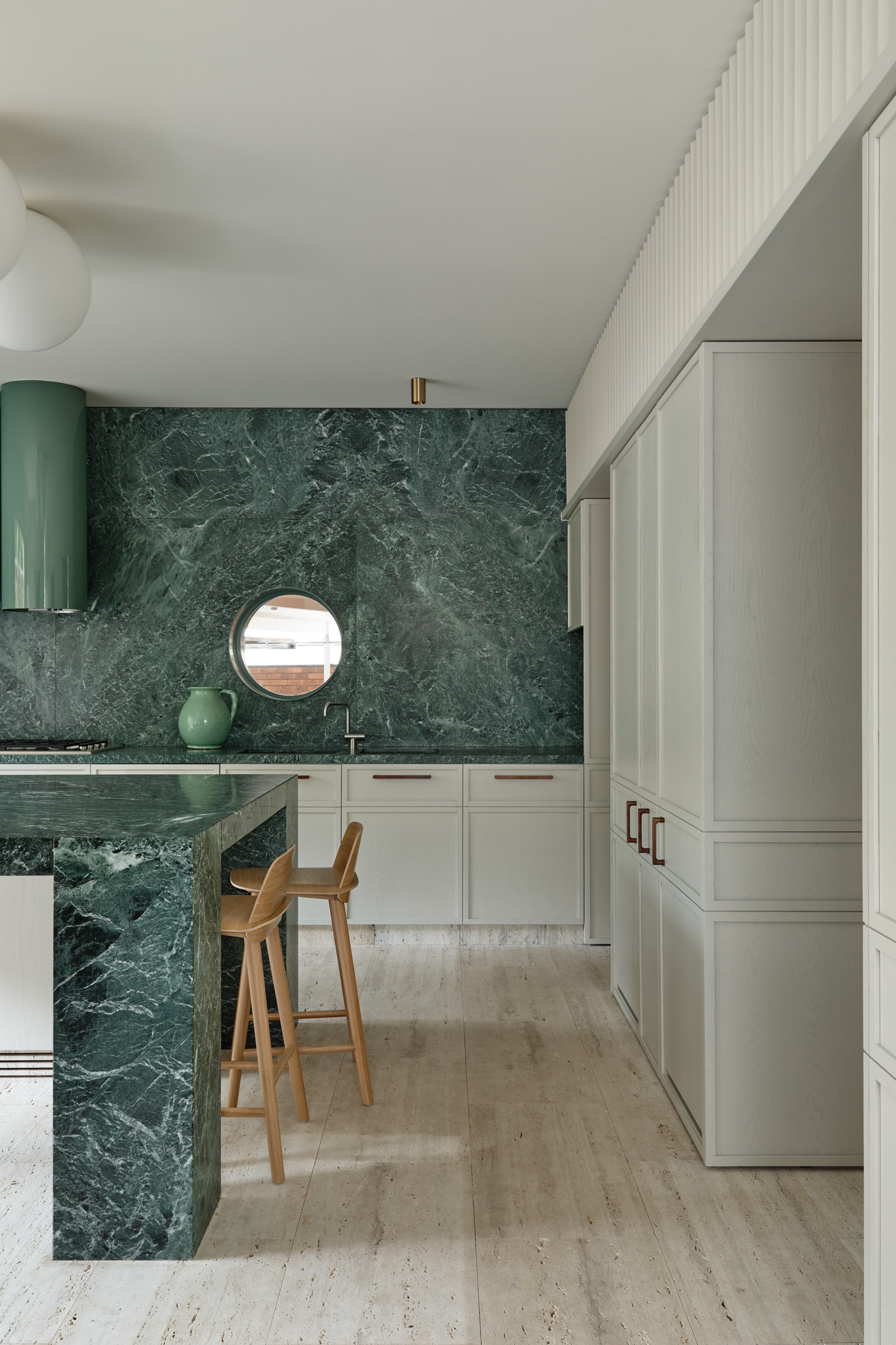 A kitchen with green marble counter tops, and white cupboards.
