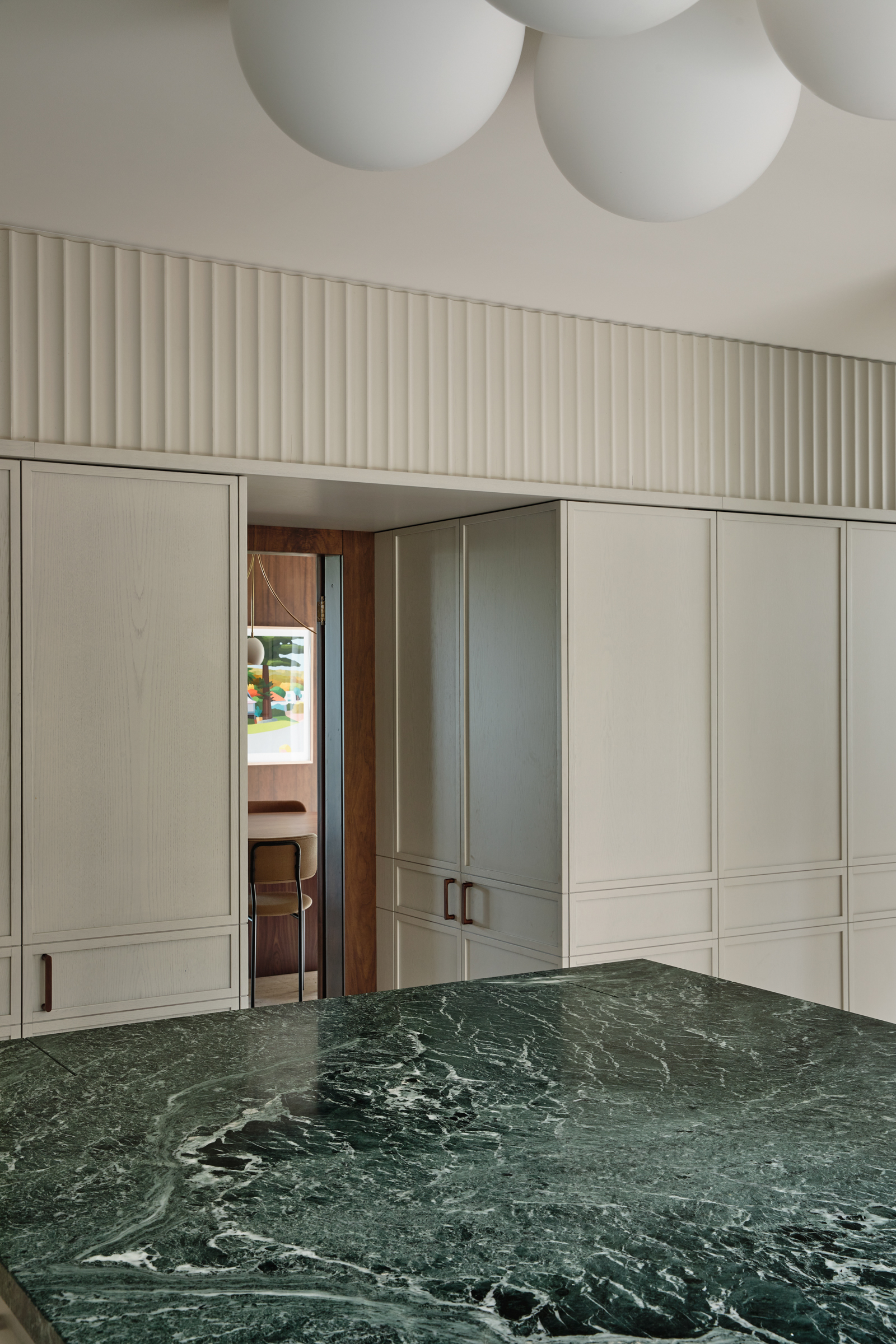 A kitchen with a green marble counter top, and white cupboards.