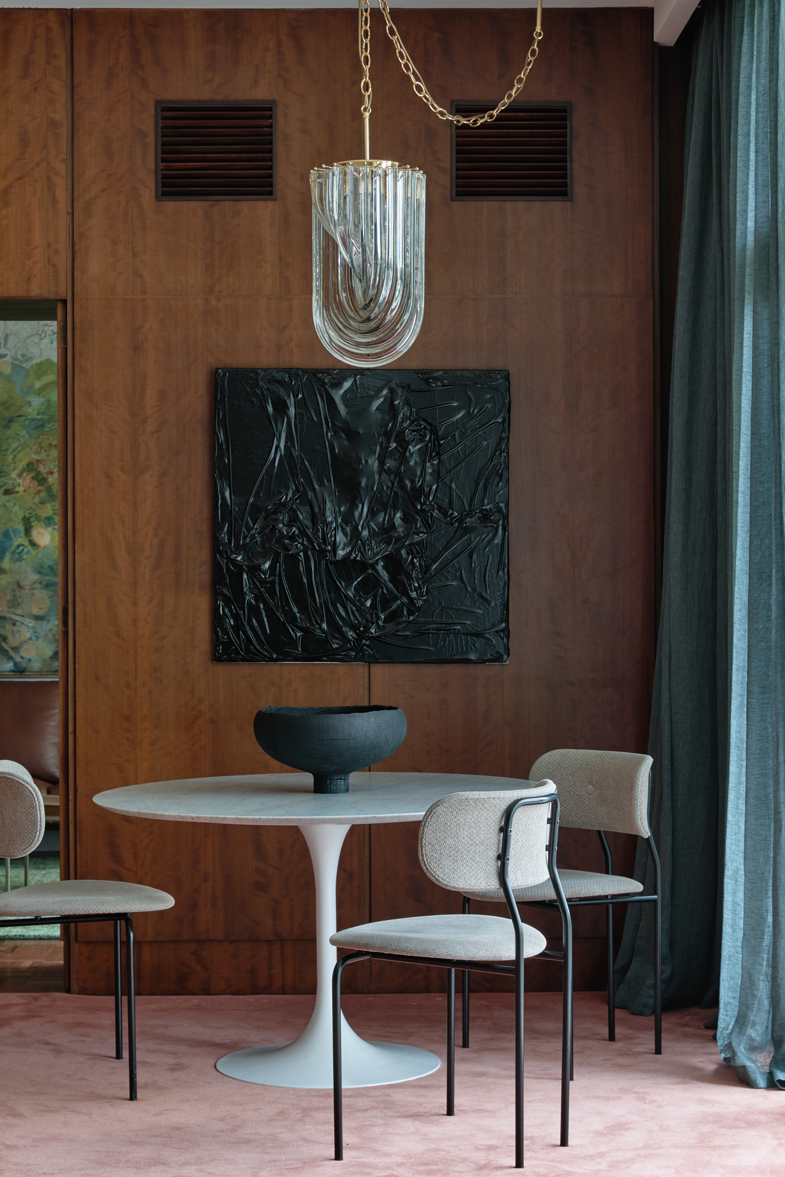 A dining room with pink carpet, wooden panelling walls and a small table and chairs.