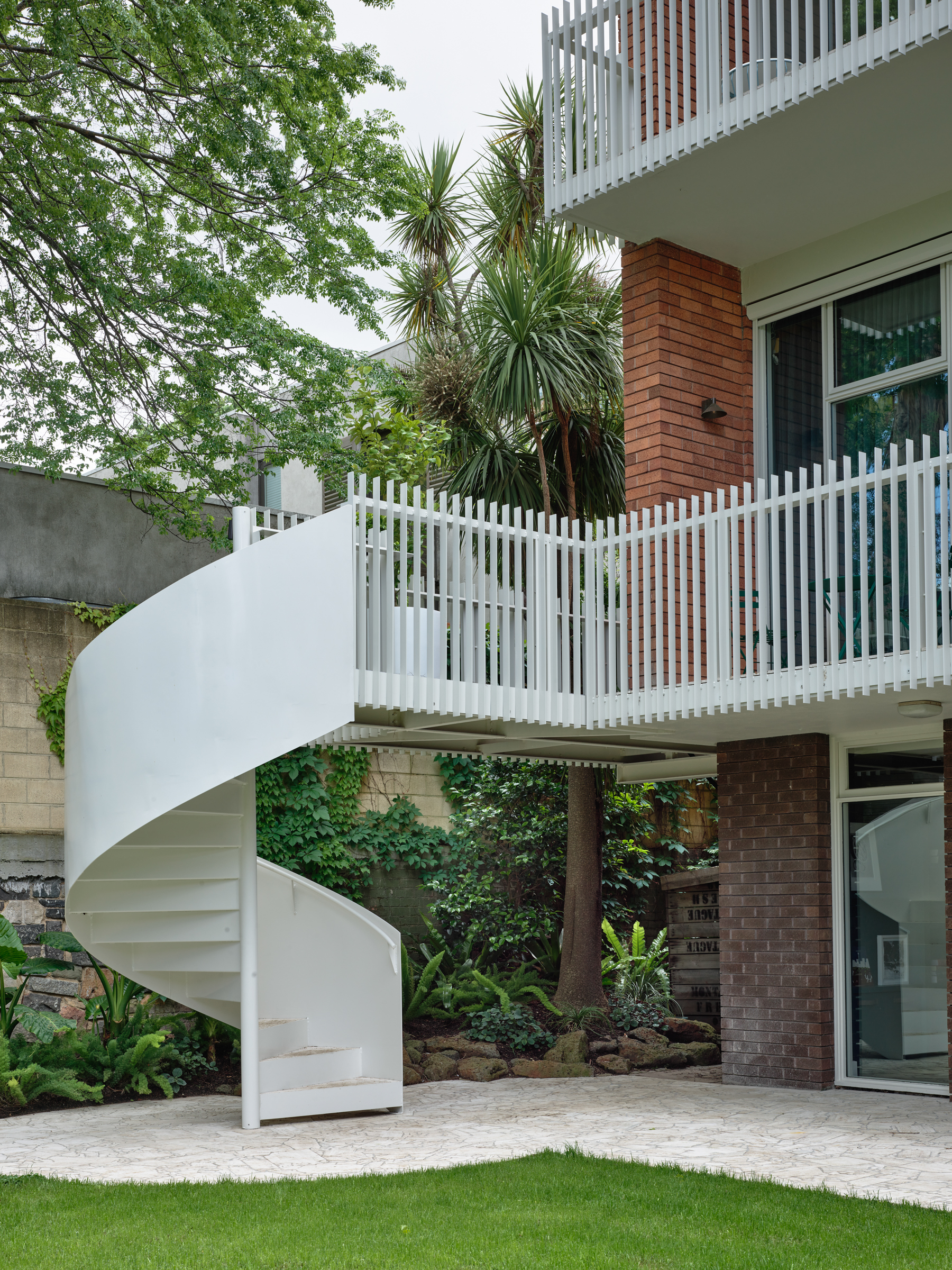 A spiral staircase leading to a balcony in a backyard.