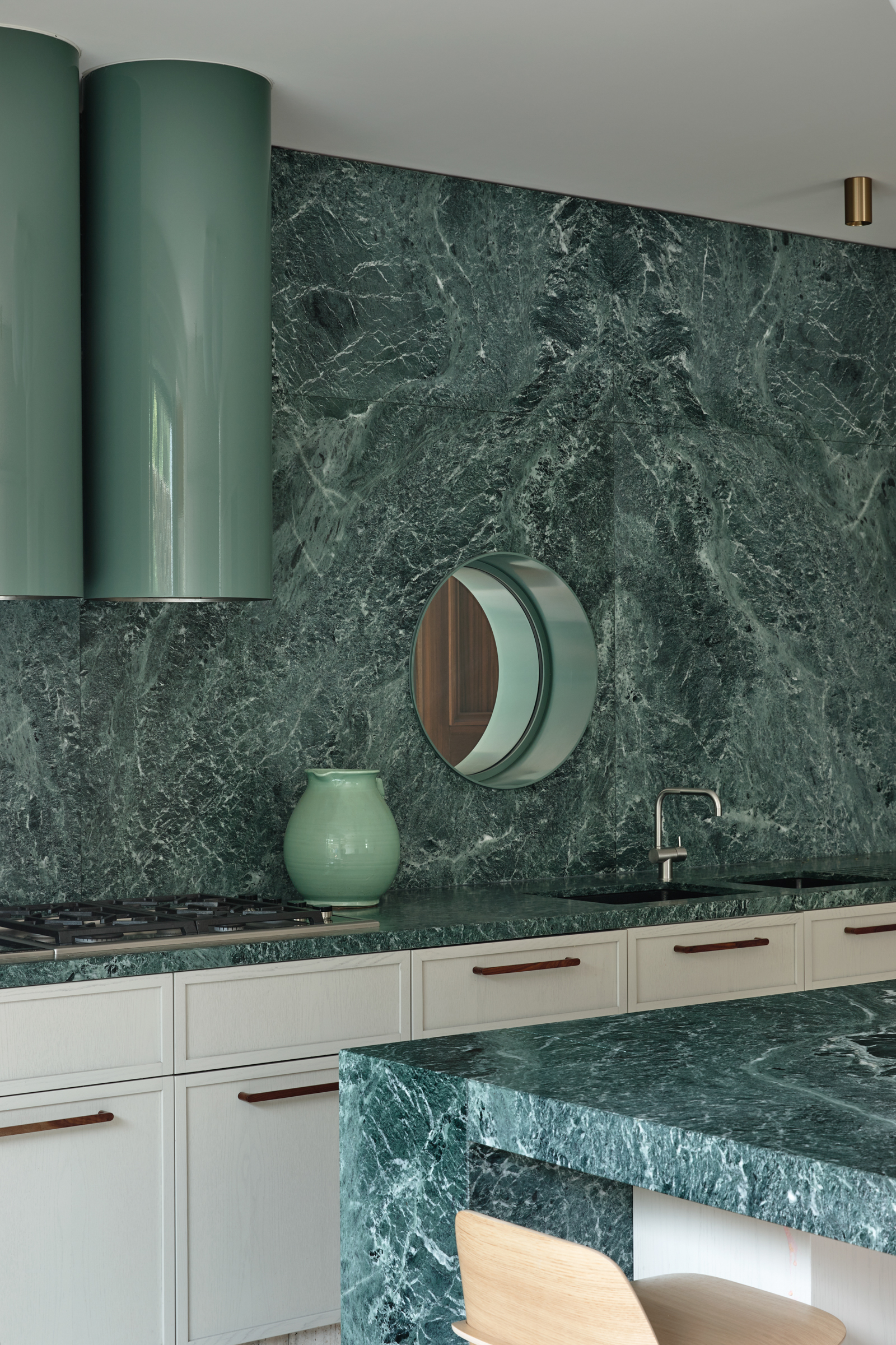A kitchen with green marble counter tops and a circular window.