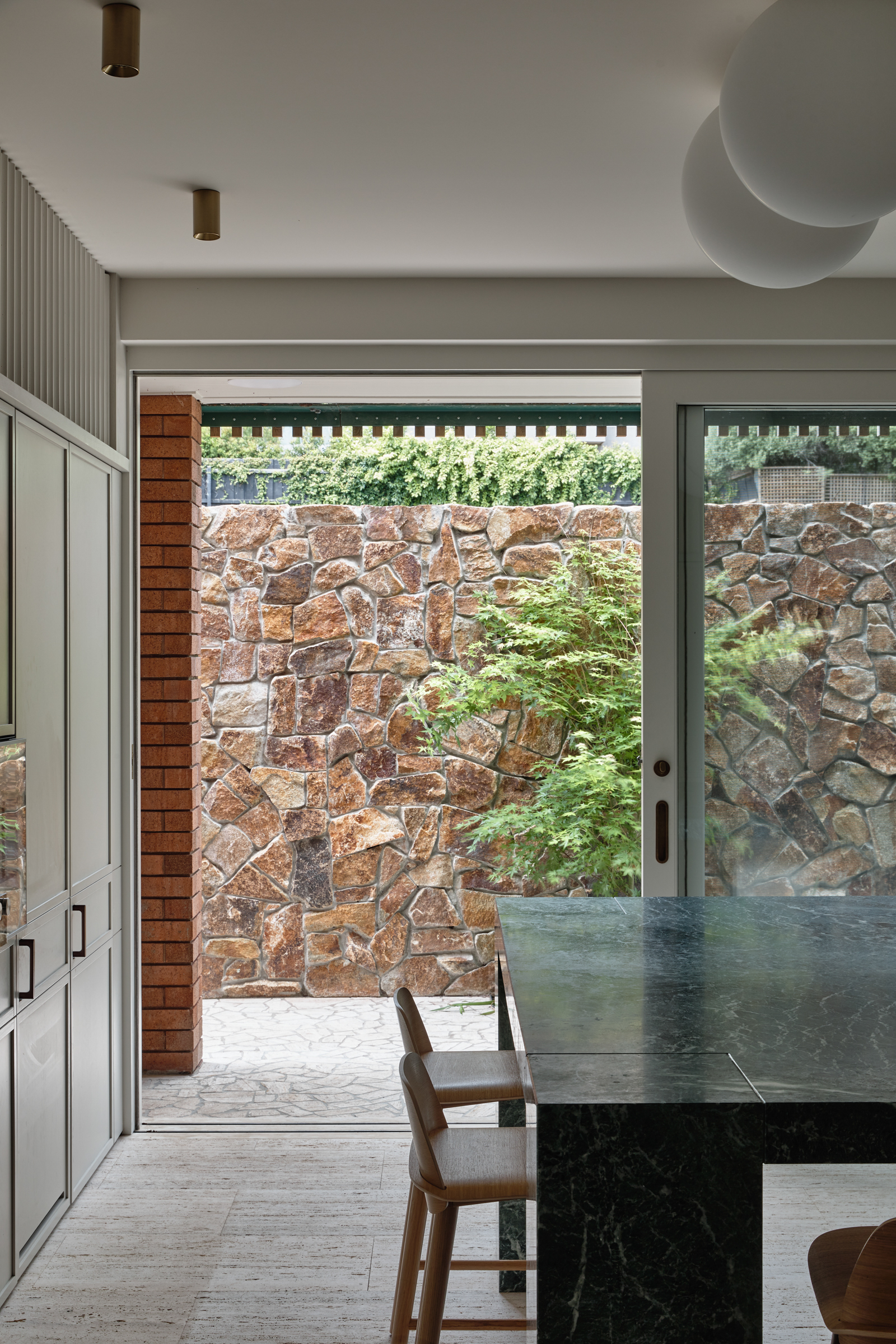 A kitchen dining table made of green marble, looking out onto a stone patio.