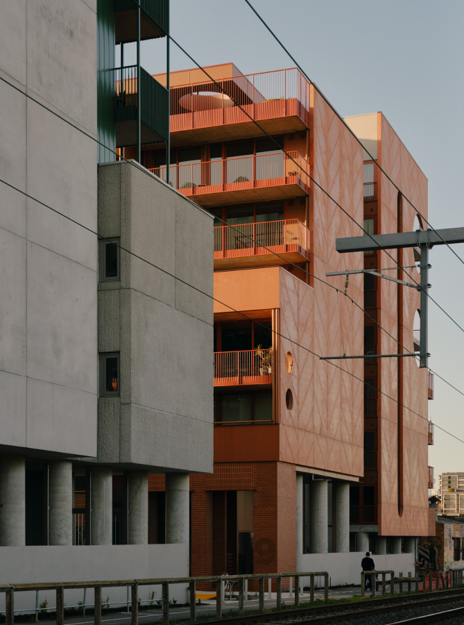 a precast building with balconies and a train line with a street light.