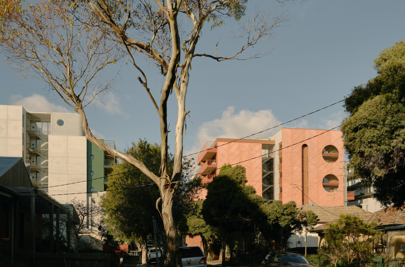 a view of two multi-storey precast concrete buildings from a suburban street.