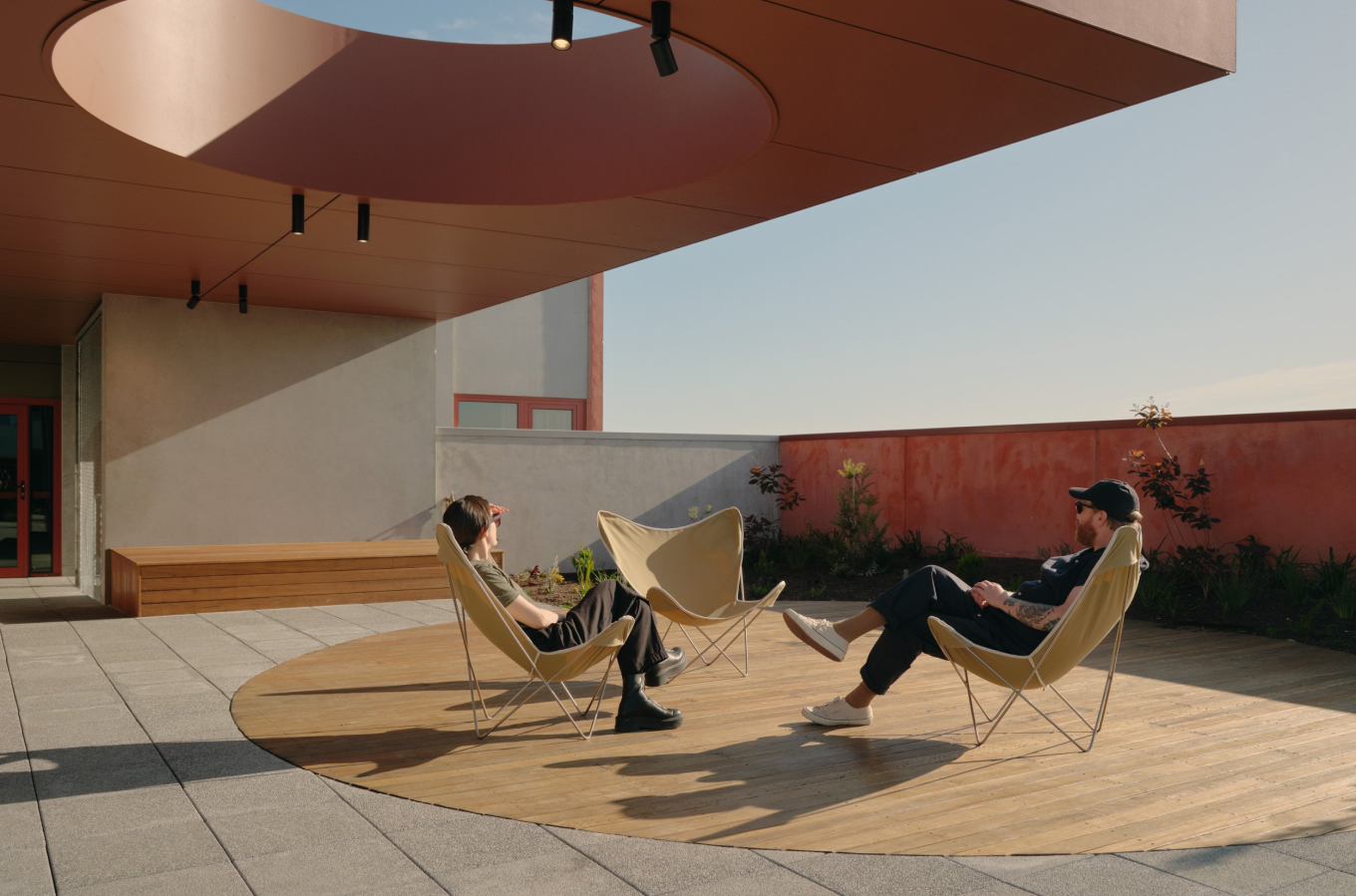 a man and woman sitting in chairs on a rooftop terrace.
