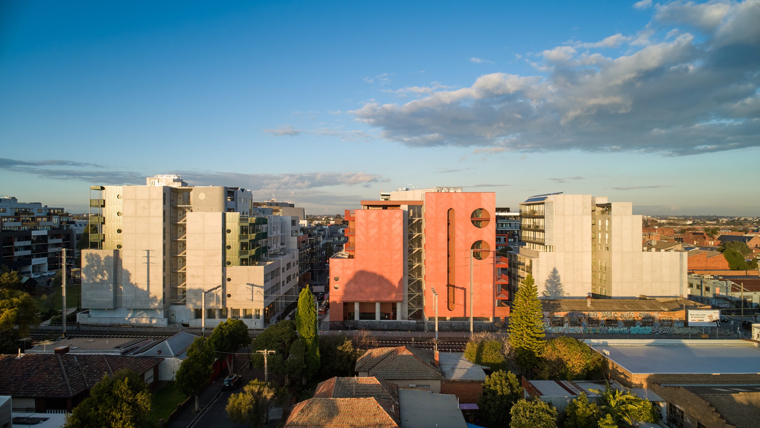 a group of multi-storey buildings with trees and a blue sky.