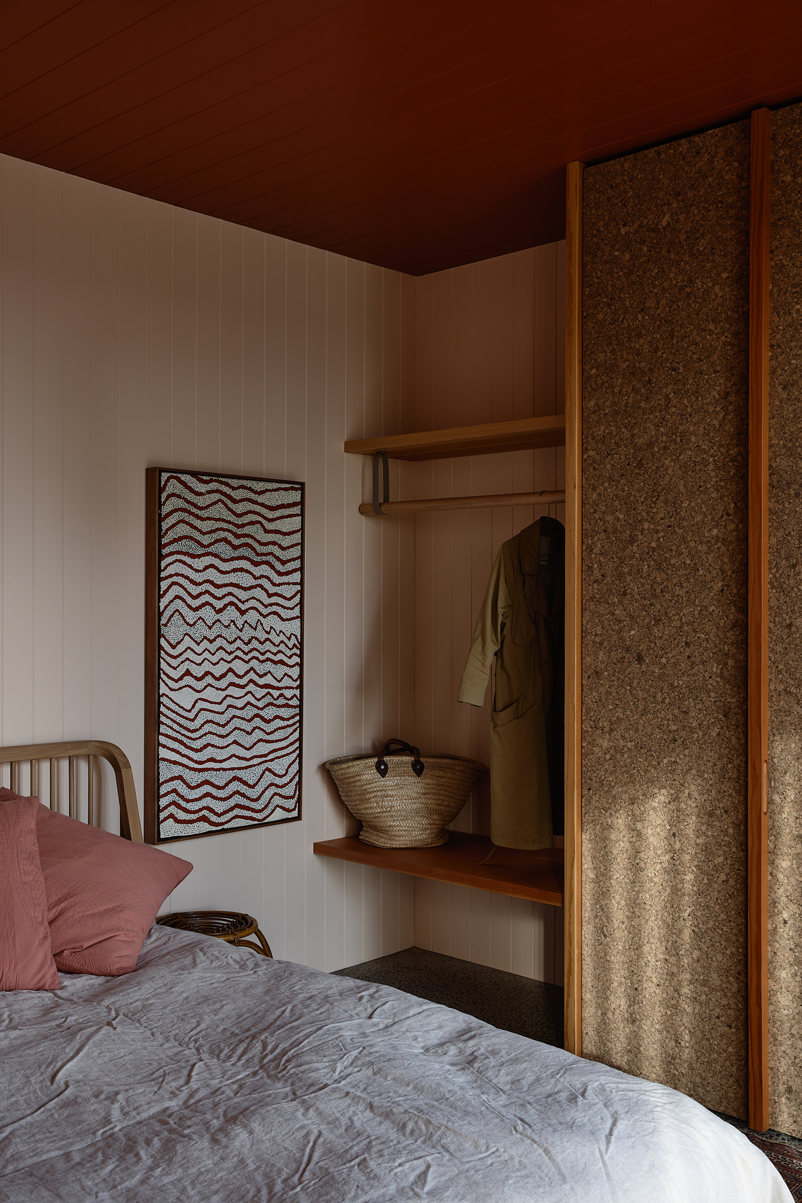 A bed in a bedroom, with shelving and a cupboard.