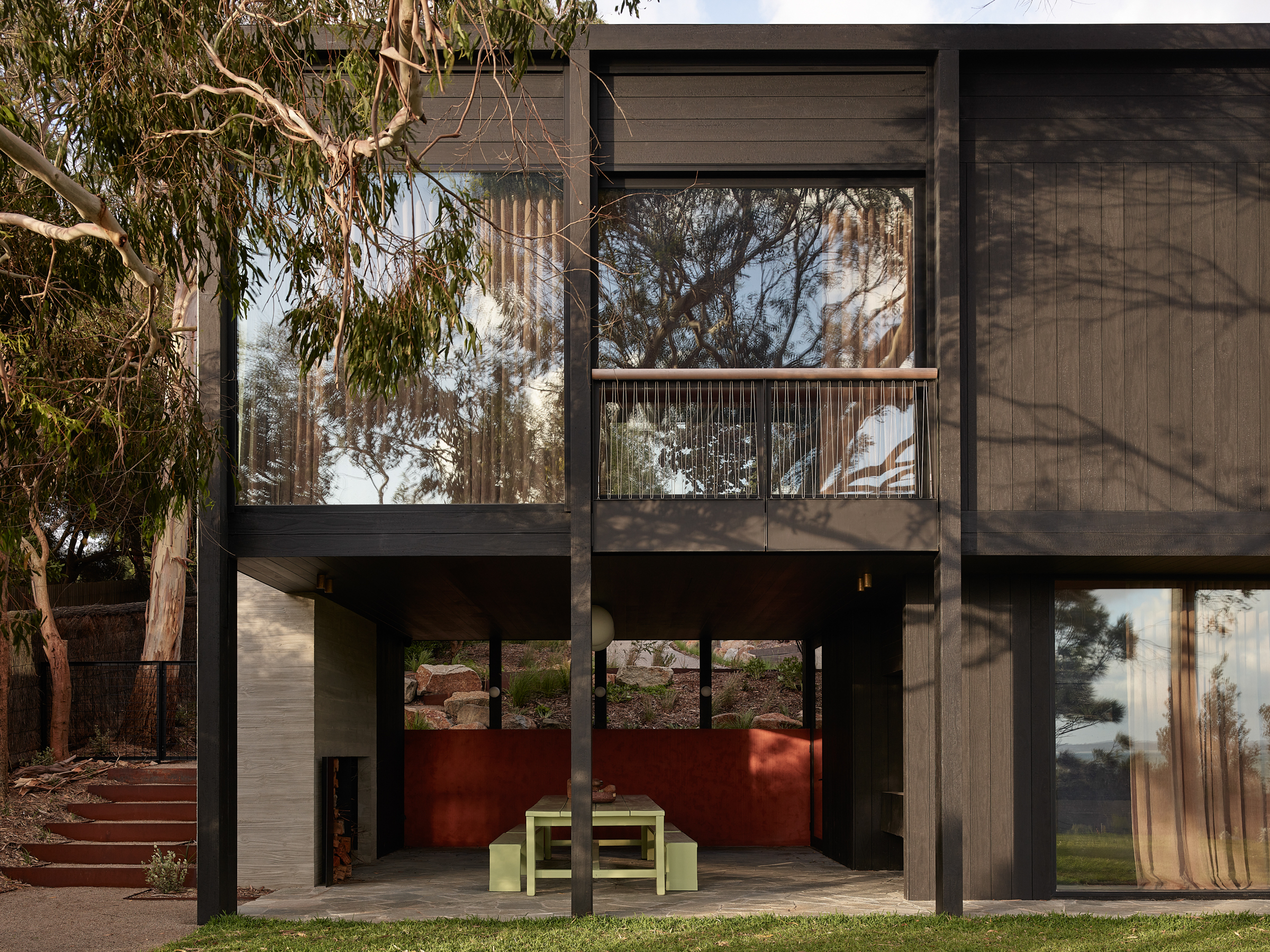 A two storey house with stairs leading to an outdoor dining area.