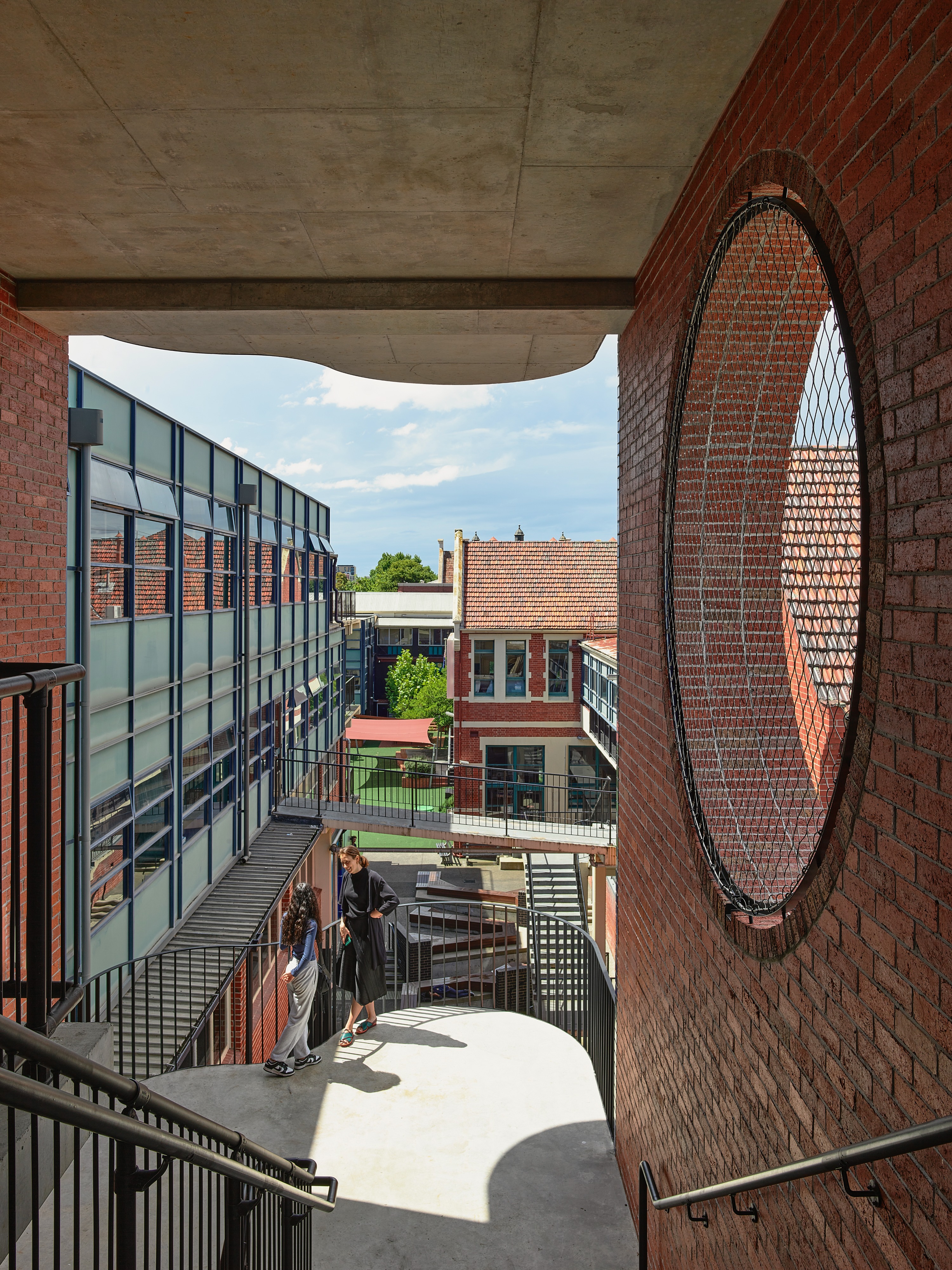 two people standing on a staircase in a brick building with a large circular window.