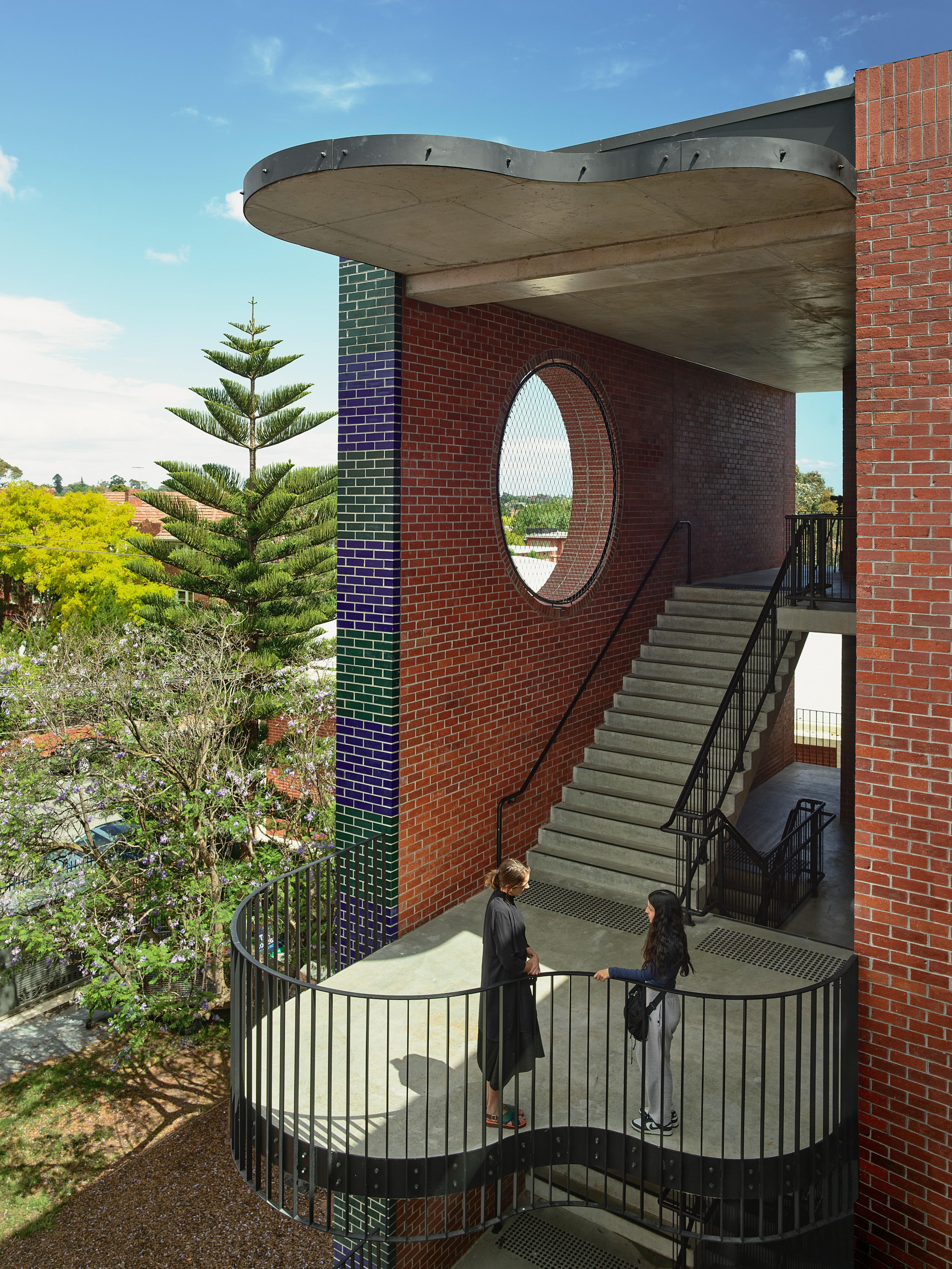 two people standing on the landing of a staircase in a brick building.