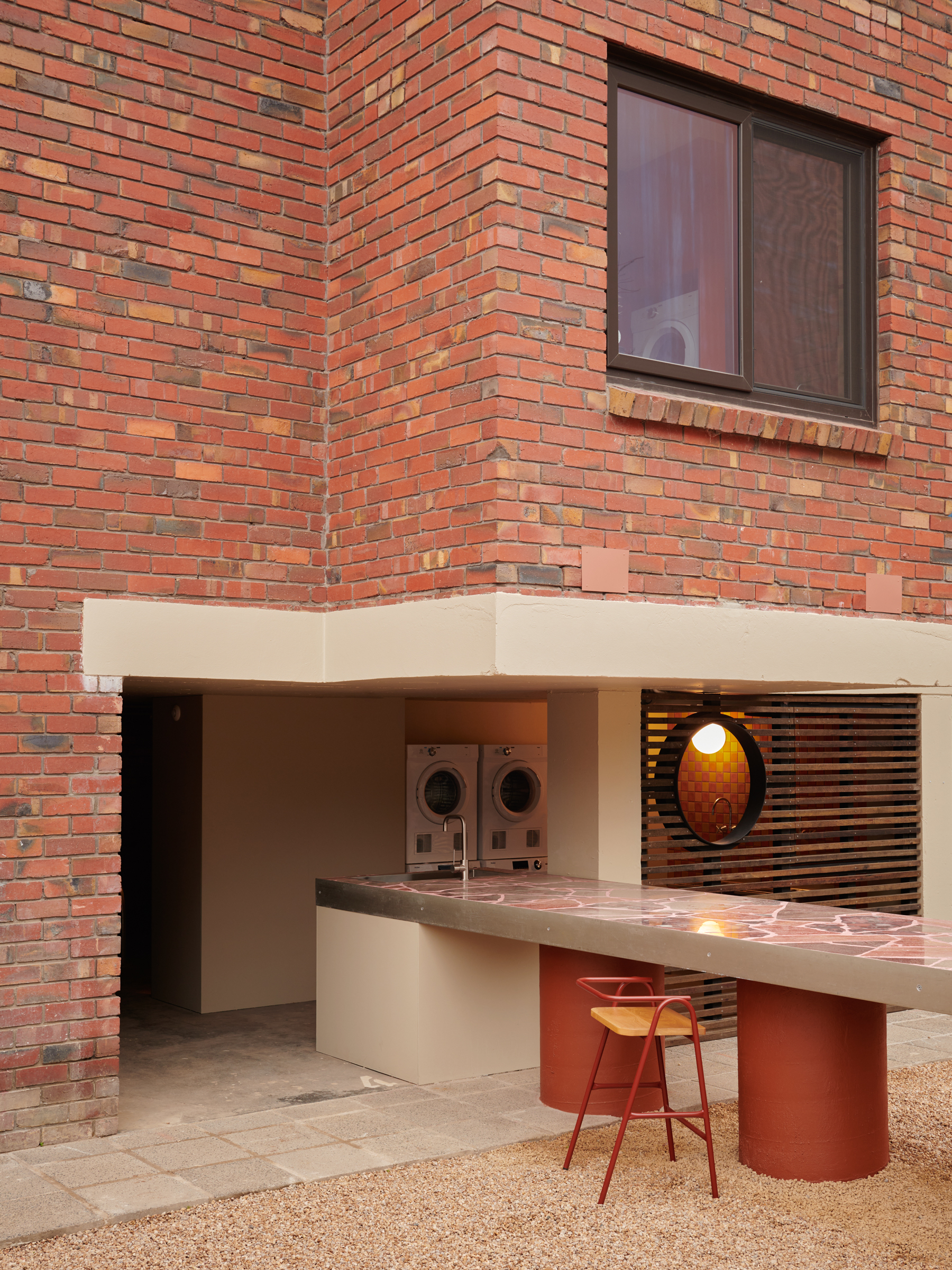 a brick building with a long central table extending from the laundry to the courtyard.