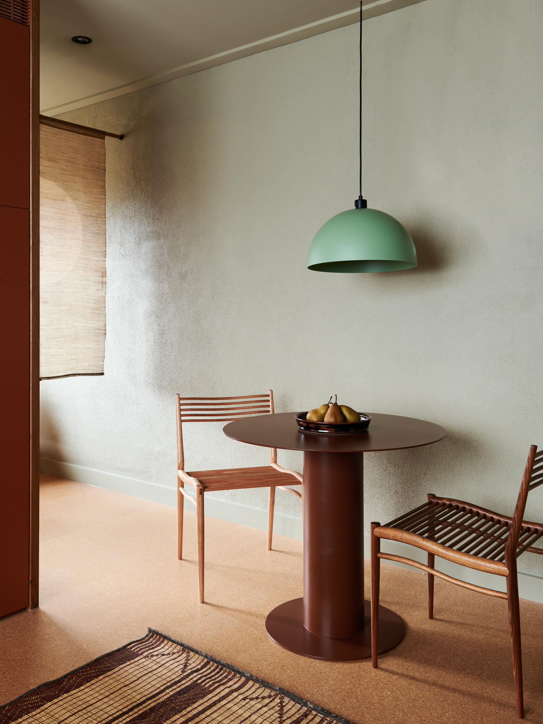a table and chairs in a room, with a ceiling light hanging from above.
